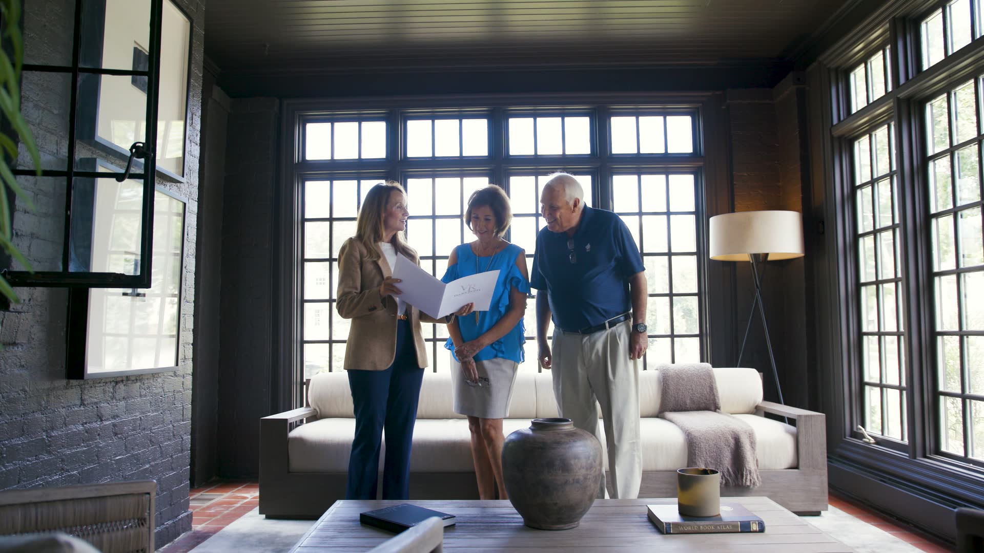 A Village Realty agent going over paperwork with clients in a sunroom