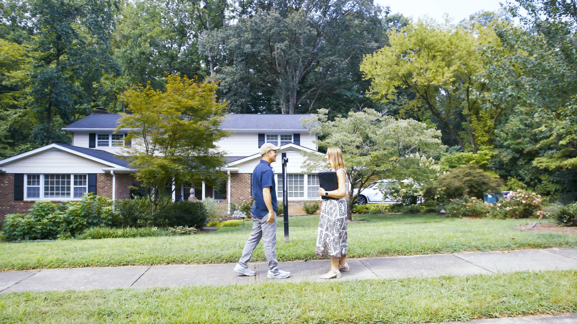 A Village Realty agent walking a client up to a mid-century split-level home