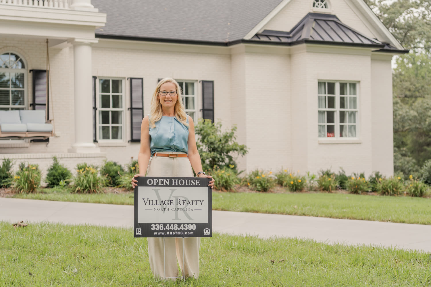 A Village Realty agent placing an Open House sign in front of a listed home